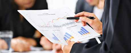 Businesswoman examining graphs with other working people on background